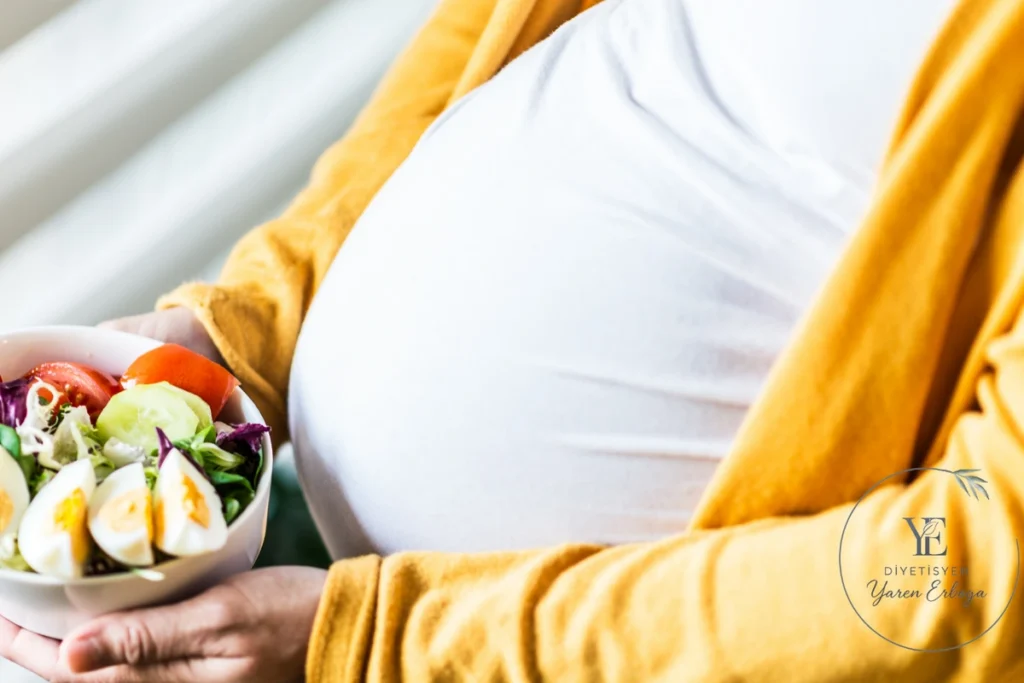 Hamile kadının elinde haşlanmış yumurta ve taze sebzeler içeren salata