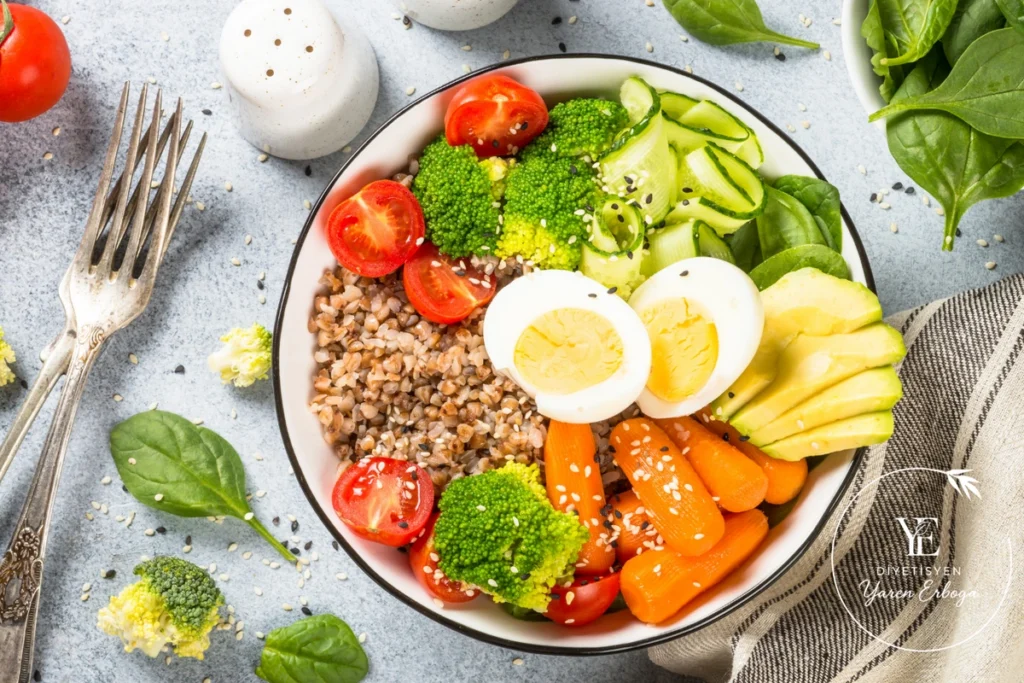 Haşlanmış yumurta, karabuğday, brokoli, havuç, avokado ve domates içeren dengeli öğün tabağı